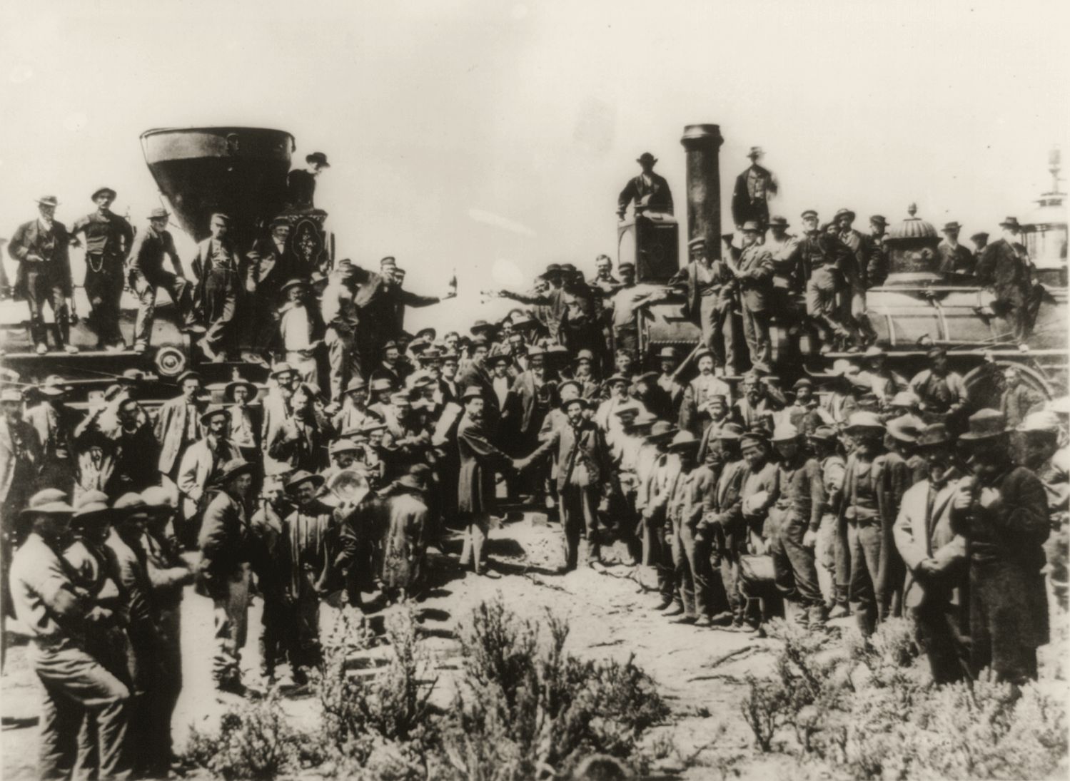 Crowds of workers cheering between two locomotives as the last spike is driven at Promontory, Utah